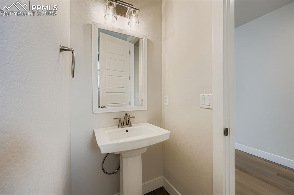 Image 11 of 28: Bathroom with dark wood-style flooring and a textured wall