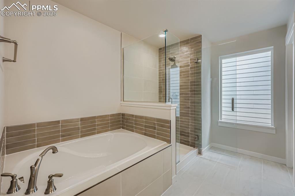 Image 16 of 28: Full bath with a shower stall, a garden tub, light tile patterned floors, a