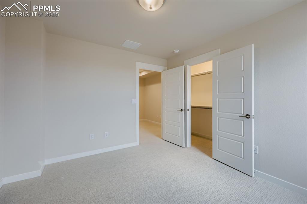 Image 19 of 28: Unfurnished bedroom featuring a spacious closet and light colored carpet