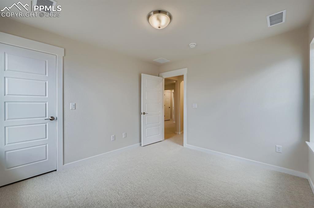 Image 21 of 28: Unfurnished bedroom with light colored carpet and baseboards