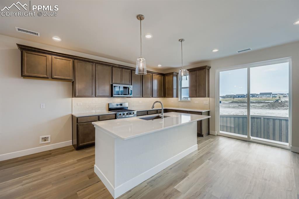 Image 7 of 28: Kitchen featuring tasteful backsplash, a kitchen island with sink, decorati