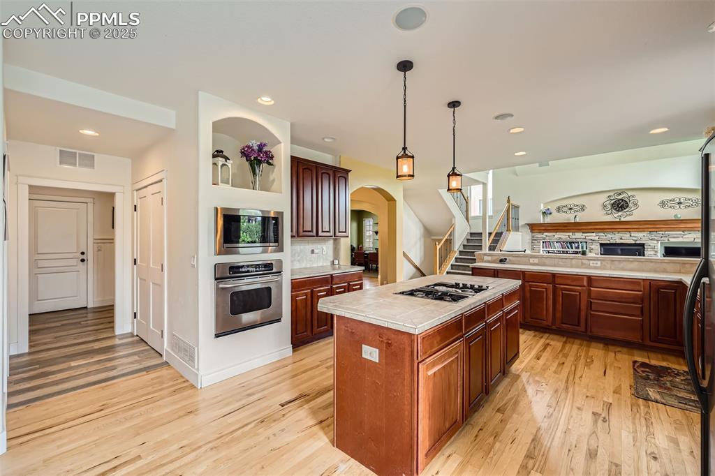 Image 10 of 28: Kitchen with stainless steel appliances, light hardwood floors, arched walk