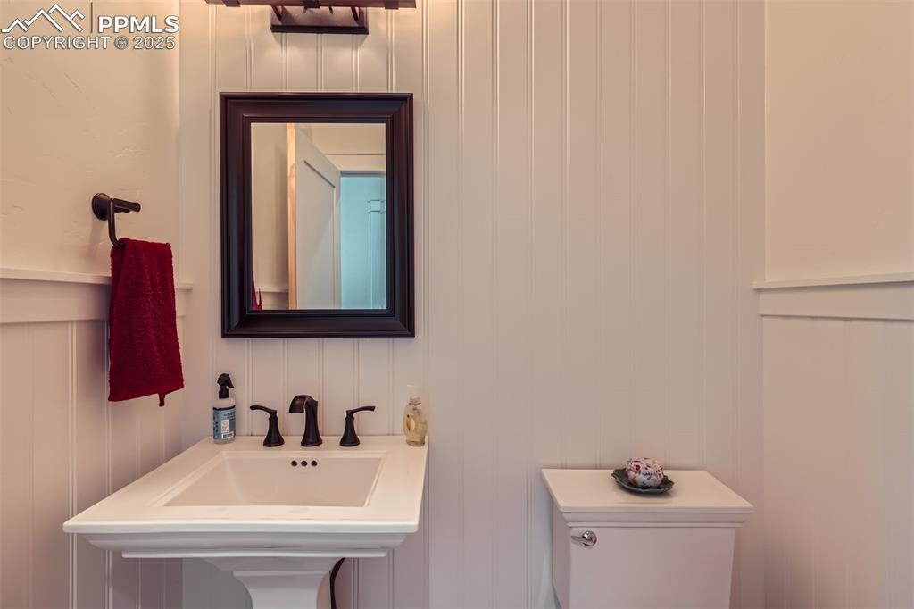 Image 12 of 28: Half-bathroom with a decorative wall wainscot and toilet