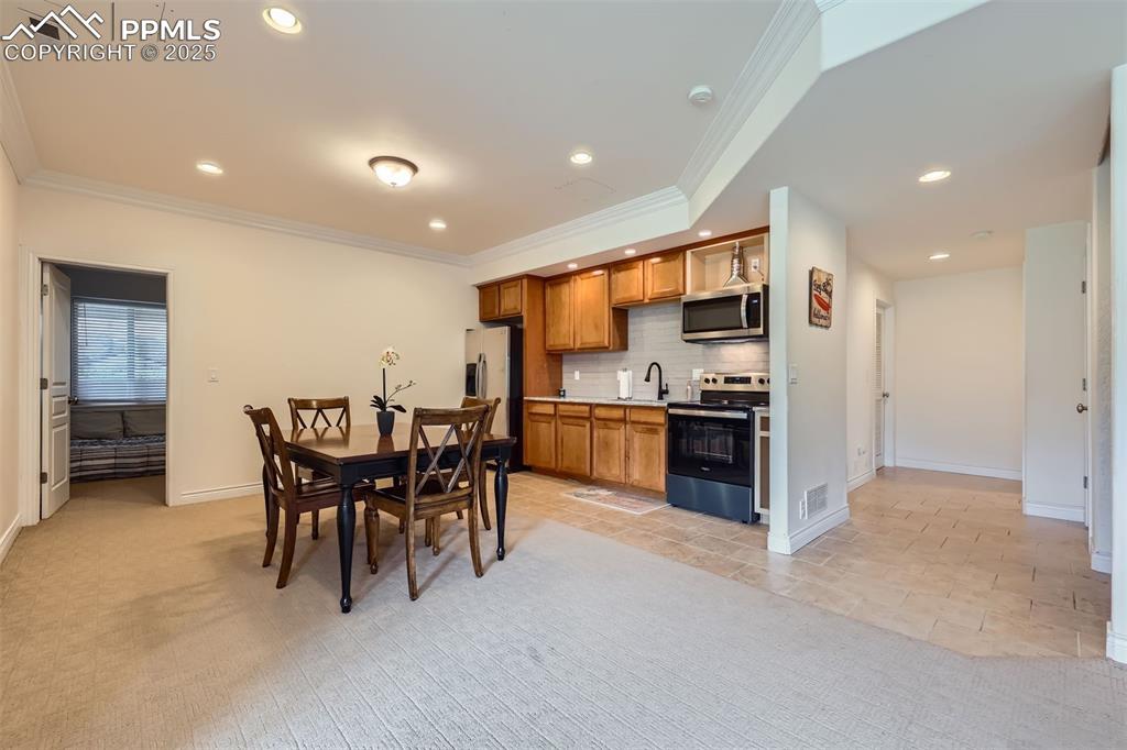 Image 25 of 28: Basement dining room featuring recessed lighting, crown molding, and light