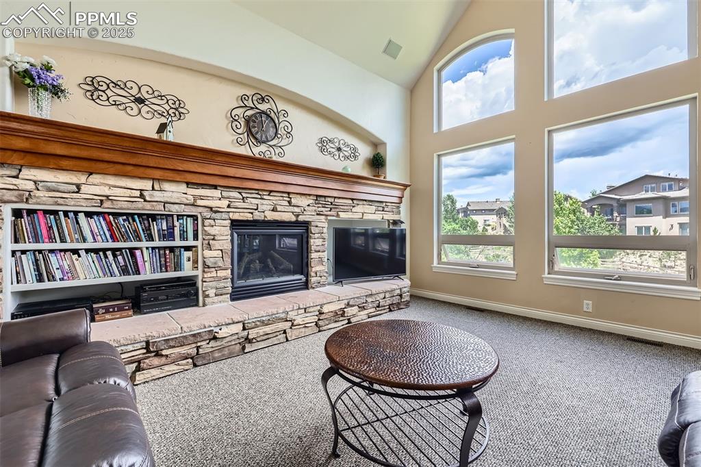 Image 6 of 28: Carpeted living room featuring a fireplace and high vaulted ceiling