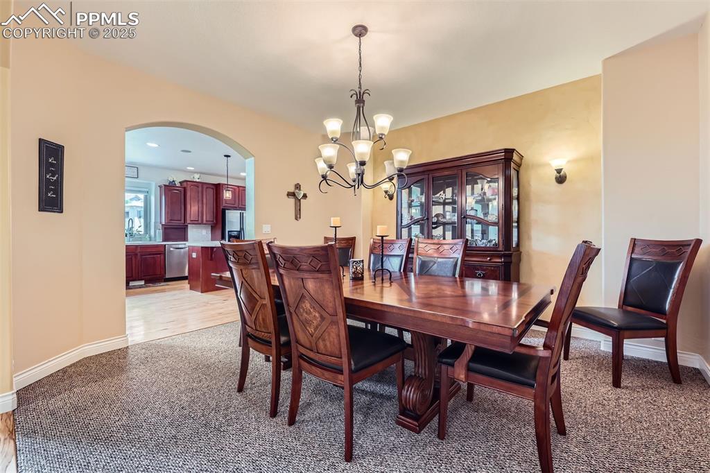 Image 7 of 28: Dining area featuring arched walkways, a chandelier, and light carpet
