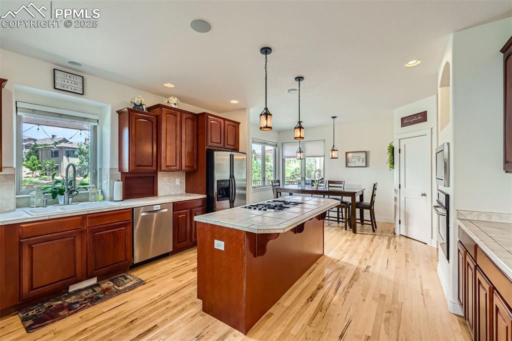 Image 9 of 28: Kitchen featuring stainless steel appliances, tile countertops, a center is