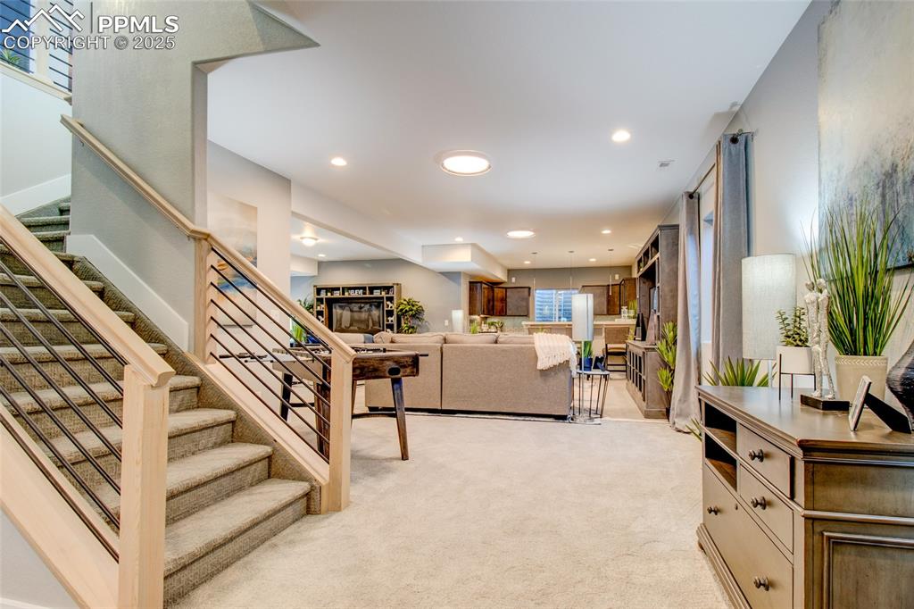 Image 23 of 30: Living room featuring light carpet, stairway, and recessed lighting