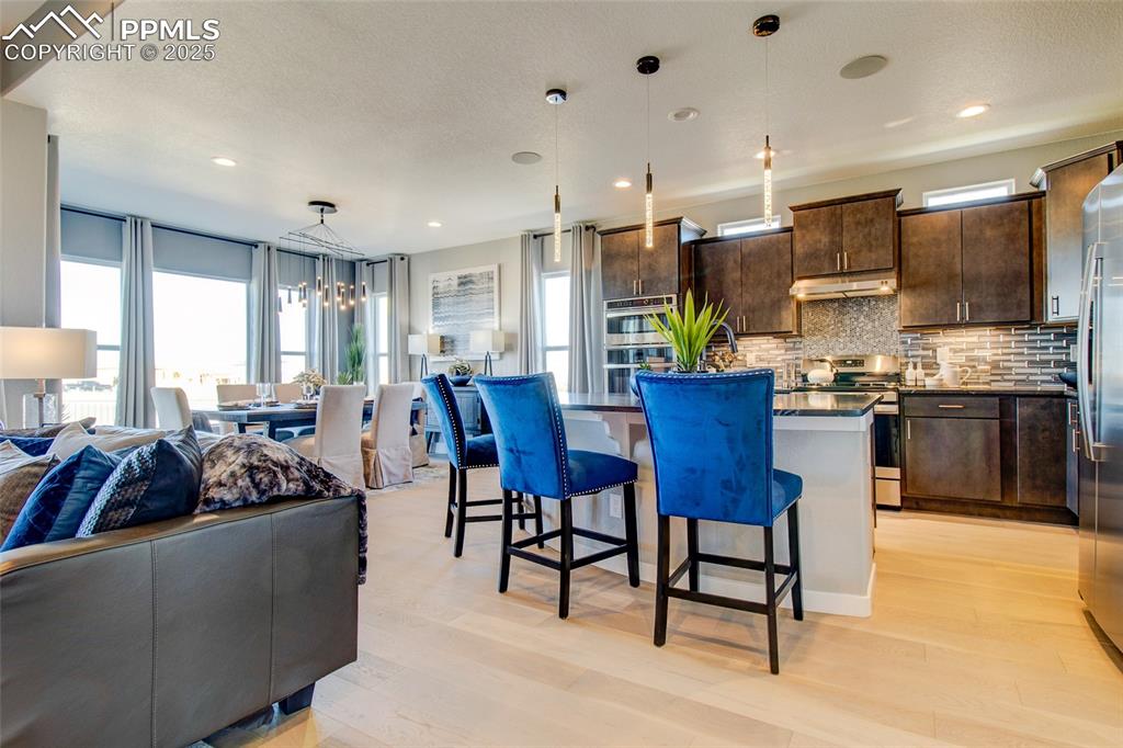 Image 6 of 30: Kitchen featuring open floor plan, dark countertops, a breakfast bar, taste