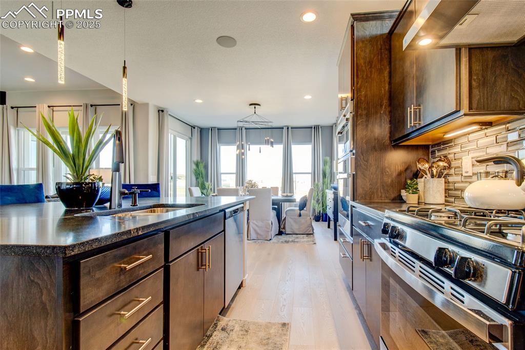 Image 9 of 30: Kitchen featuring light wood-style flooring, stainless steel appliances, ra