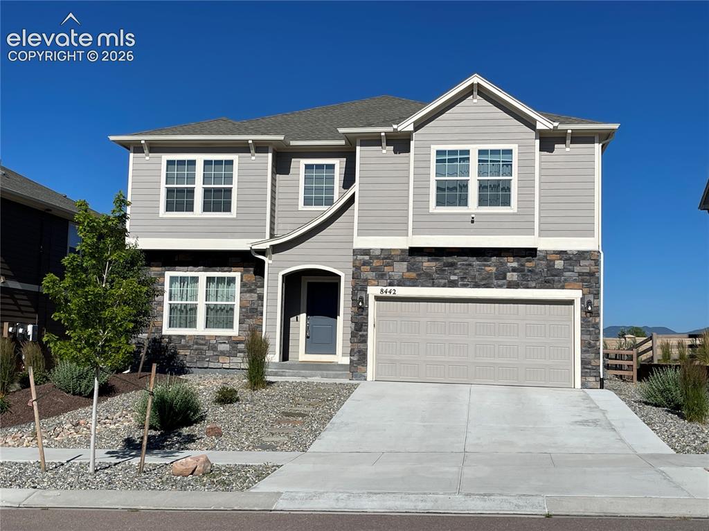 Image 1 of 25: Two-story residence featuring light gray siding and dark stacked stone acce