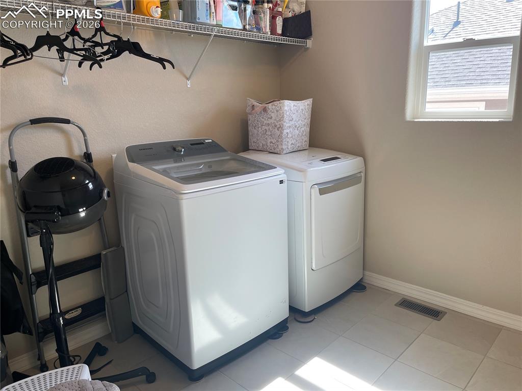 Image 10 of 26: Laundry room with separate washer and dryer and light tile patterned floori