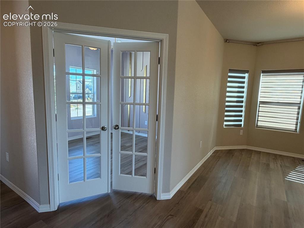 Image 12 of 24: French doors with multiple lites, wood-finish flooring, two windows with ho