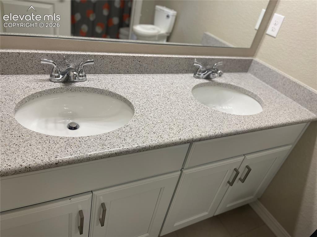 Image 13 of 25: Full bathroom with double vanity and tile patterned flooring