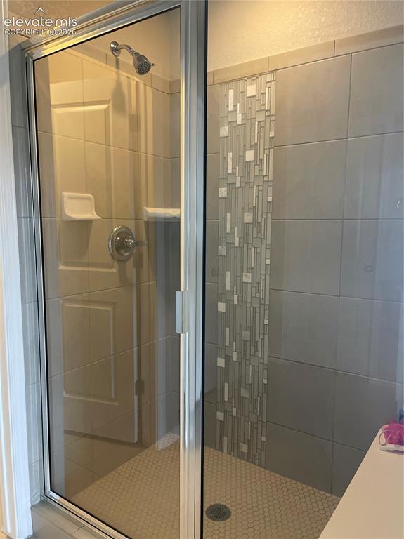 Image 14 of 25: Bathroom featuring a stall shower and a textured wall