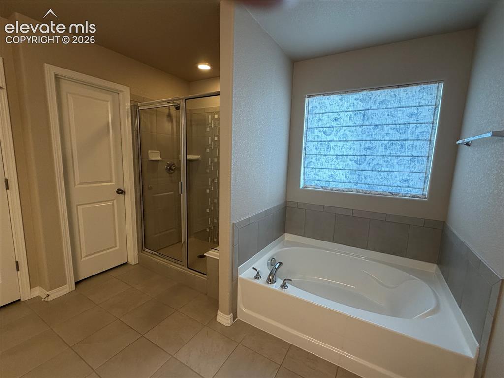 Image 14 of 24: Soaking tub with tile surround, glass-enclosed shower, and tile flooring