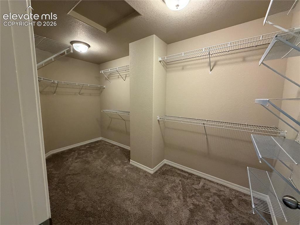 Image 15 of 24: Spacious closet with integrated wire shelving systems and warm neutral wall