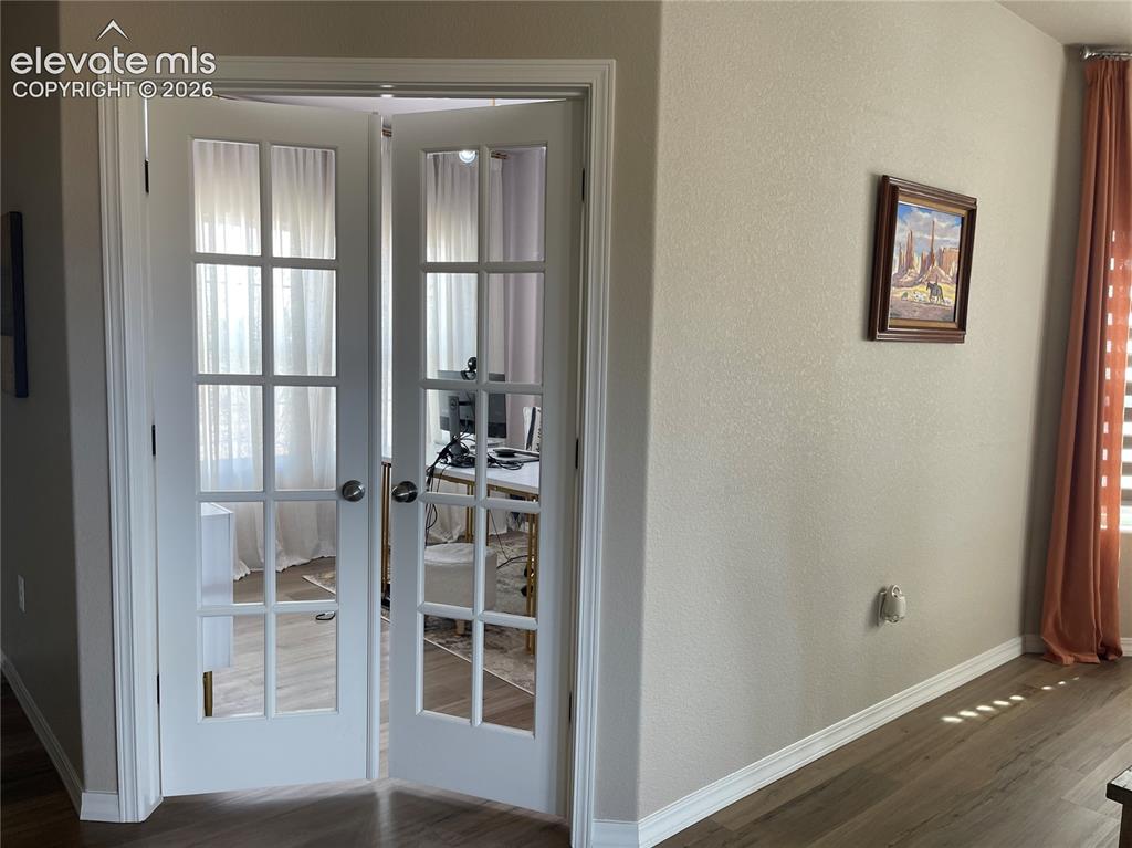 Image 18 of 25: Doorway to outside with wood finished floors, french doors, a textured wall