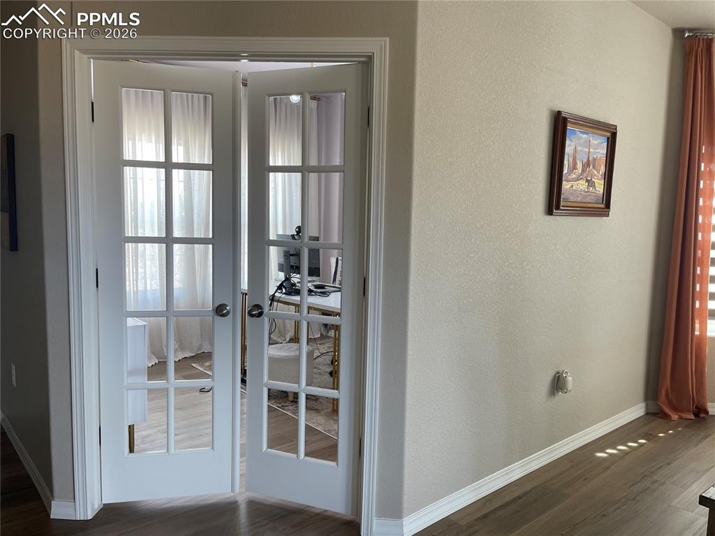 Image 19 of 26: Doorway to outside with wood finished floors, french doors, a textured wall