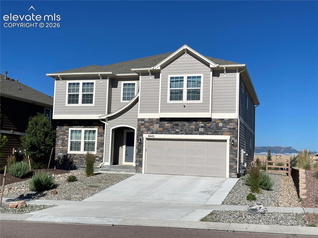Image 2 of 25: Two-story residence featuring light gray siding and dark stone veneer accen