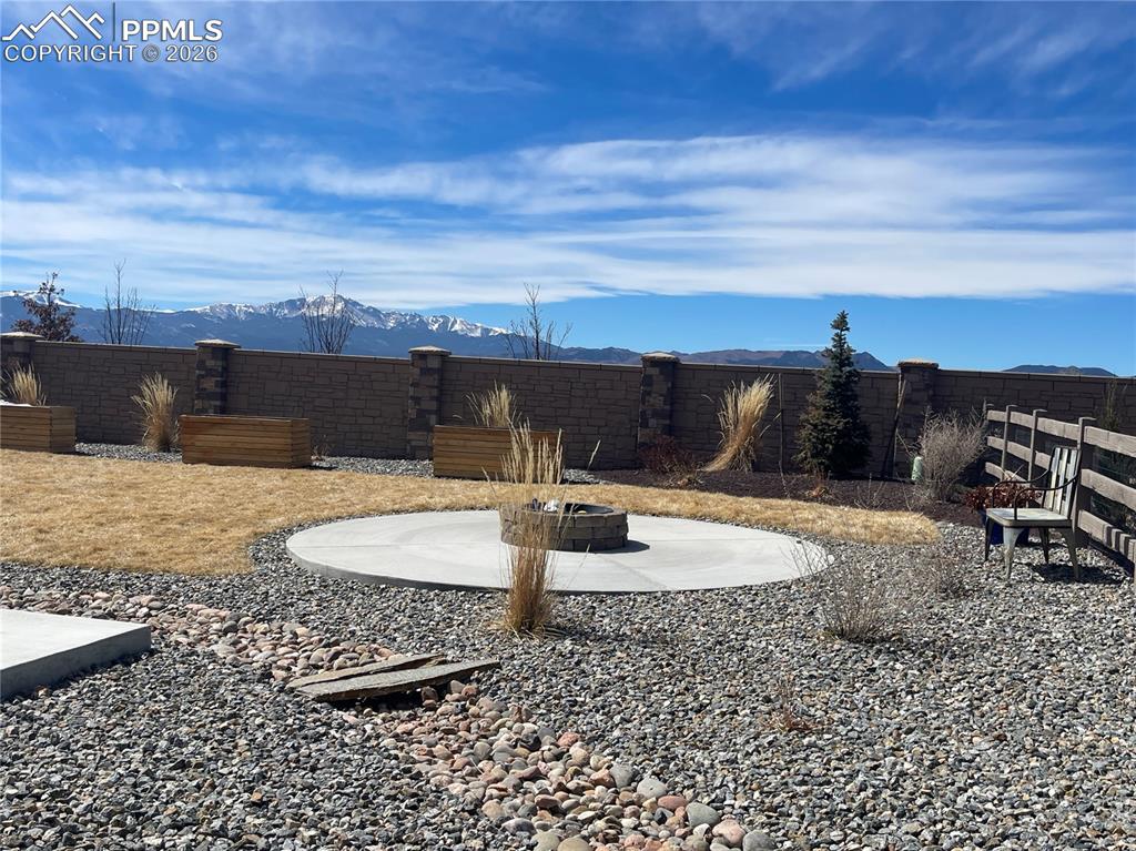 Image 22 of 26: Fenced backyard featuring a patio, a mountain view, and a fire pit