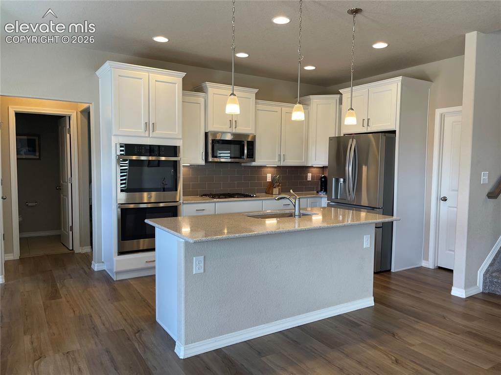 Image 3 of 25: Kitchen featuring stainless steel appliances, a center island with sink, li