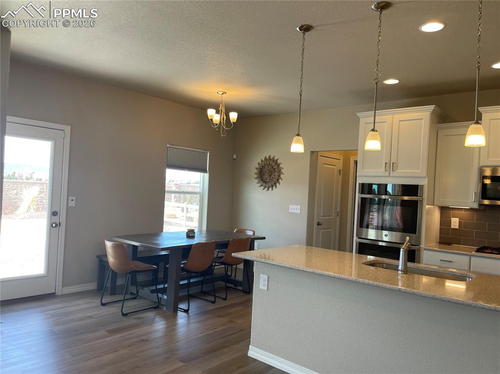 Image 5 of 26: Kitchen featuring white cabinetry, stainless steel appliances, light stone 