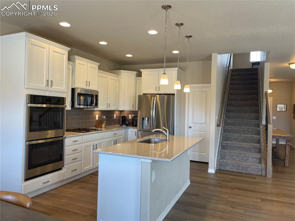 Image 6 of 26: Kitchen with stainless steel appliances, an island with sink, white cabinet
