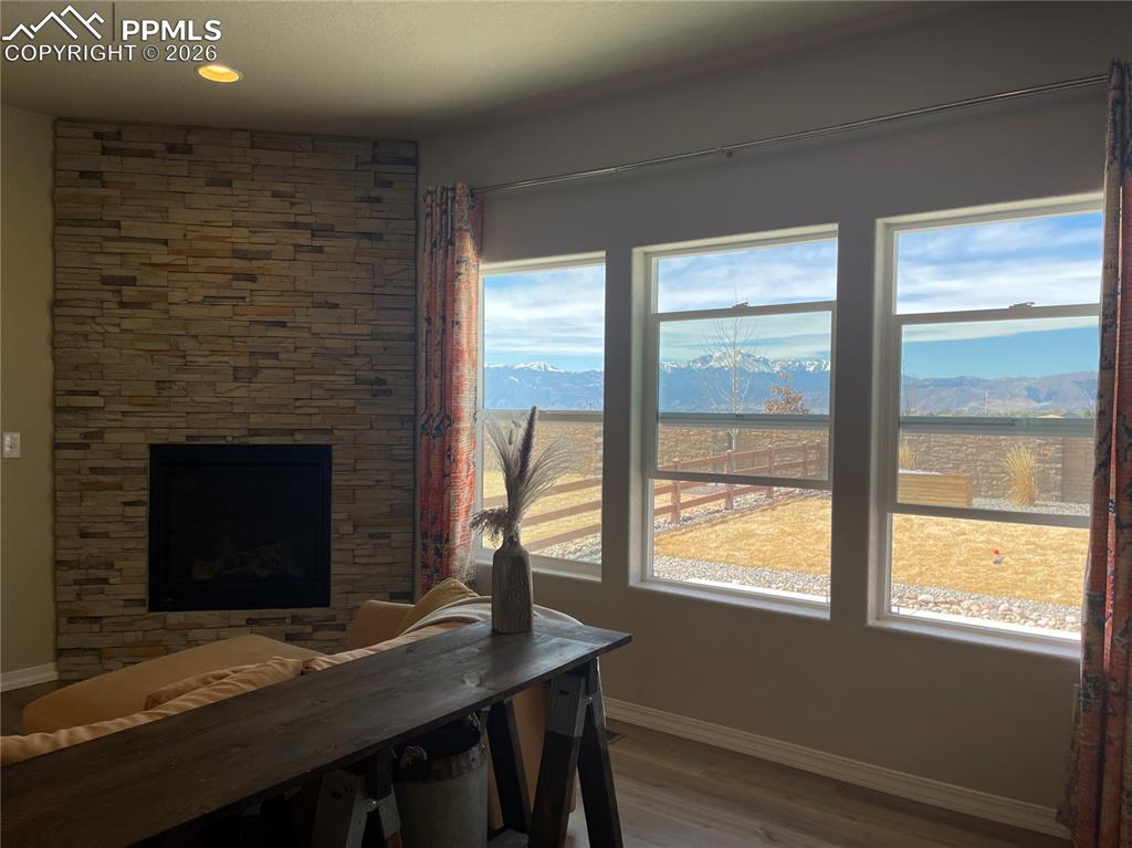 Image 7 of 26: Living room featuring a mountain view, wood finished floors, a stone firepl