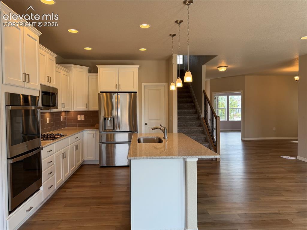 Image 7 of 24: Kitchen with white cabinetry, stainless steel appliances, and an island fea