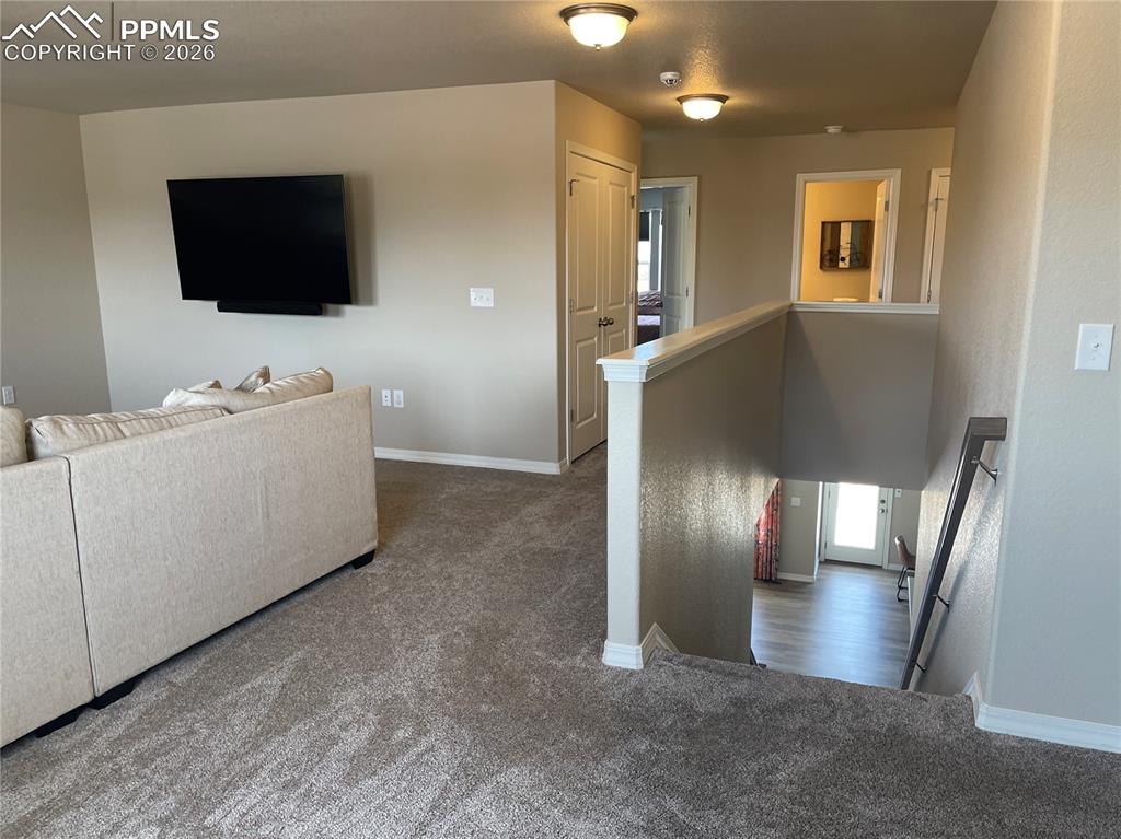 Image 9 of 26: Living room with dark carpet and baseboards