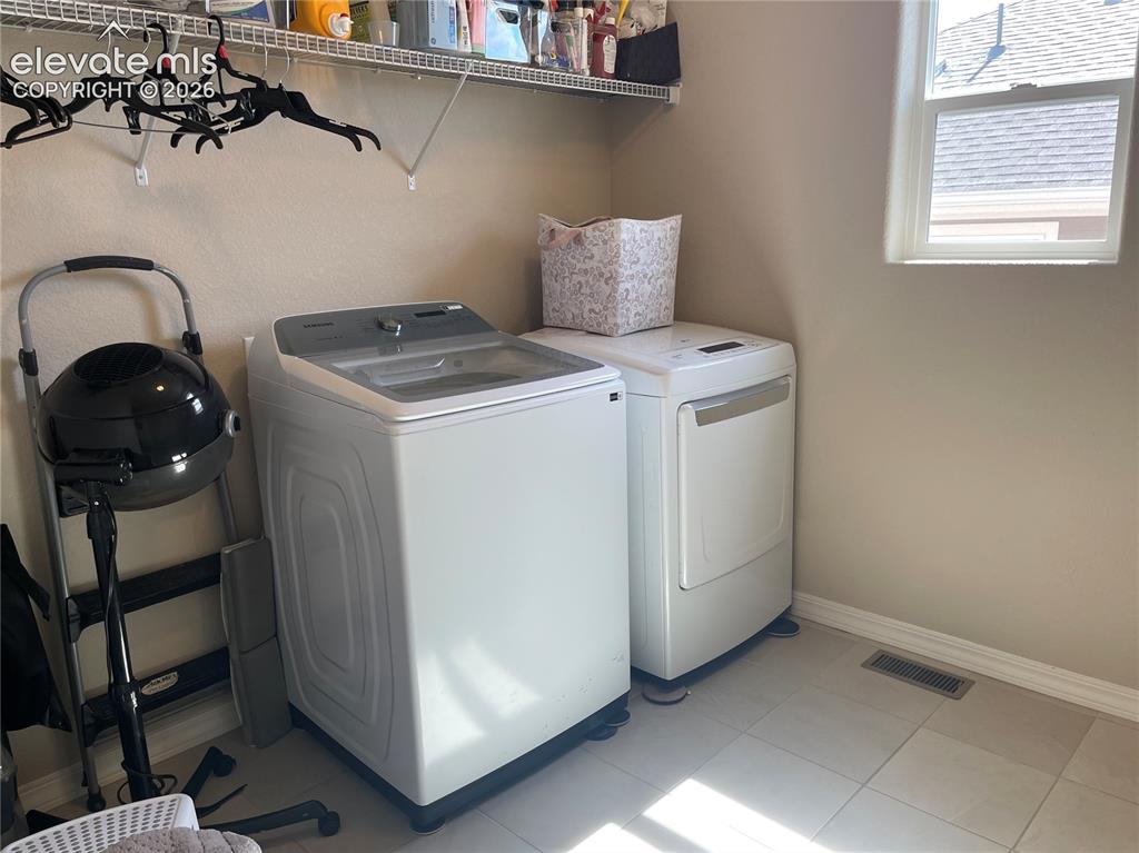 Image 9 of 25: Laundry room with separate washer and dryer and light tile patterned floori
