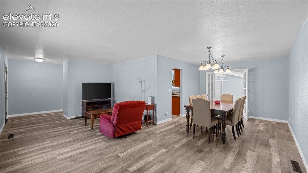 Image 10 of 39: Spacious living area featuring wood-finish flooring, a stone-front fireplac