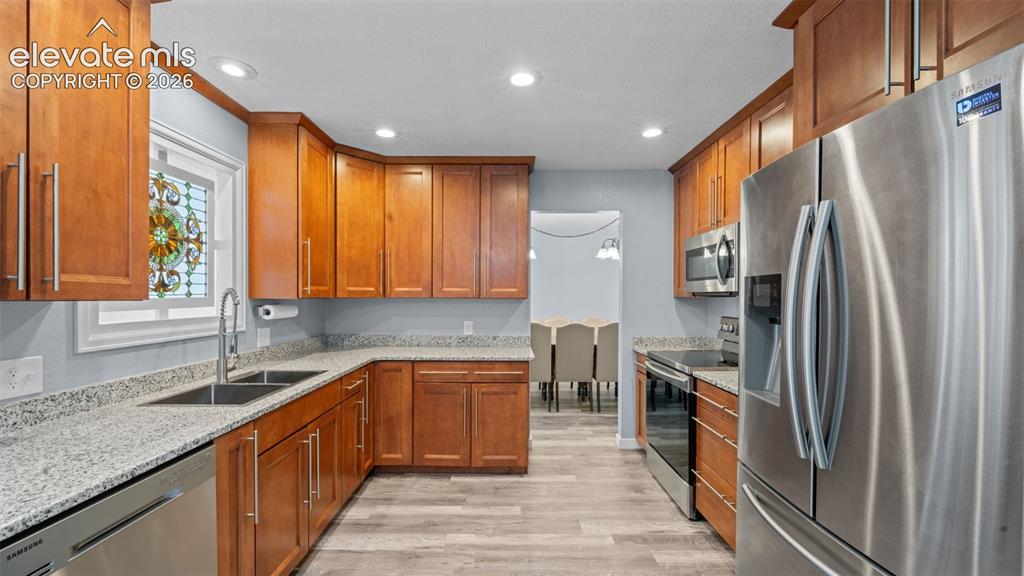 Image 11 of 39: Spacious living area featuring wood-finish flooring, vaulted ceilings with