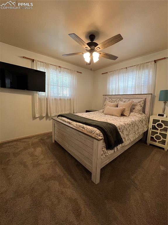 Image 11 of 29: Bedroom with dark carpet, a ceiling fan, and baseboards