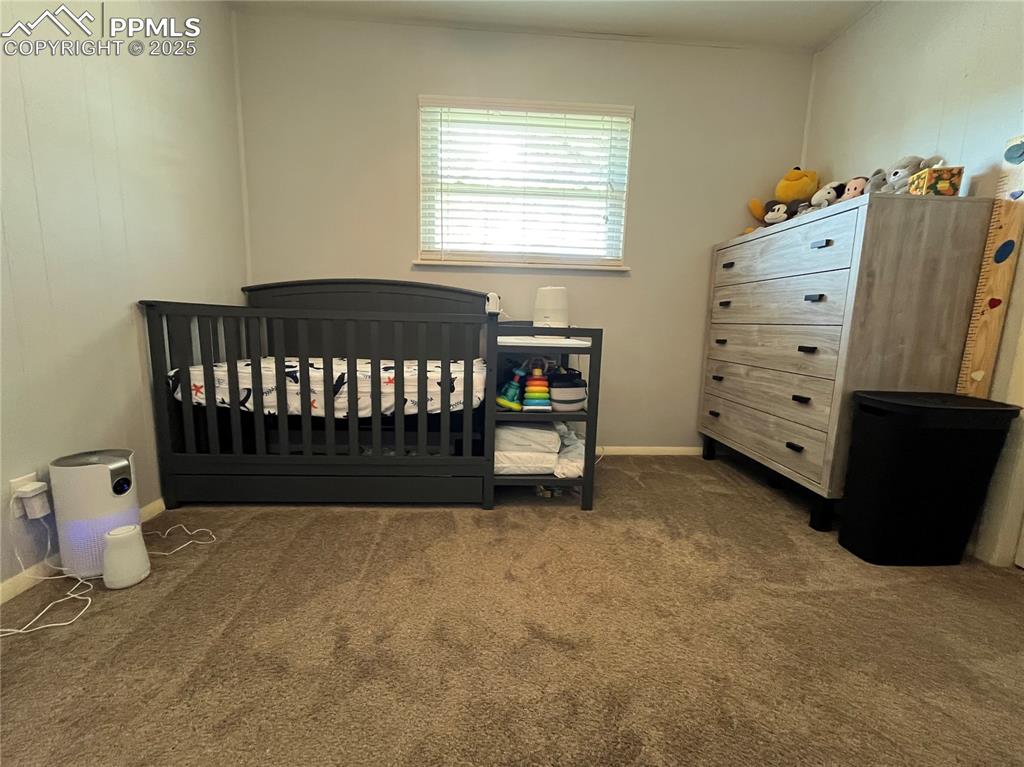 Image 13 of 29: Carpeted bedroom featuring a nursery area and baseboards