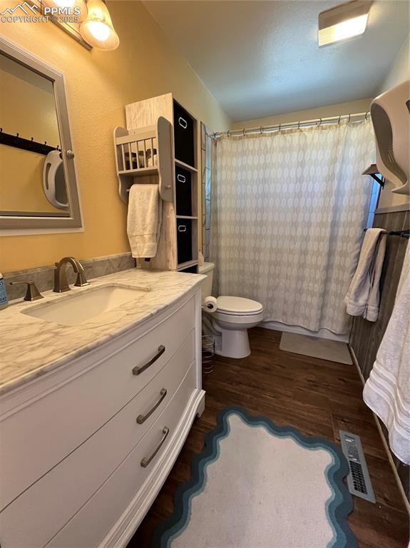 Image 17 of 29: Full bath with vanity, wood finished floors, toilet, and a shower with curt