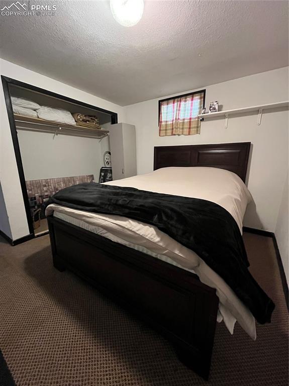 Image 24 of 29: Carpeted bedroom with baseboards and a textured ceiling