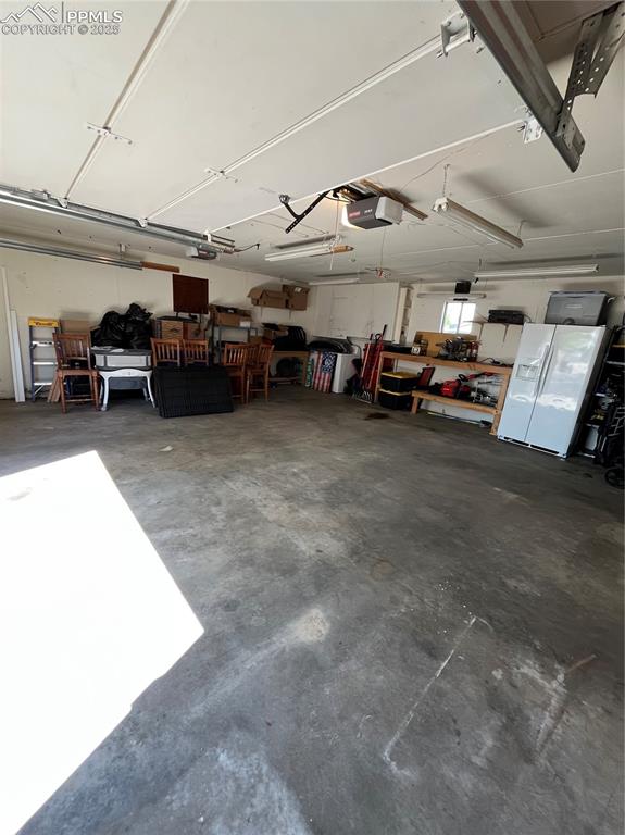 Image 26 of 29: Garage featuring a garage door opener and fridge