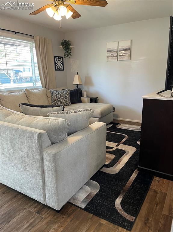 Image 7 of 29: Living area with a ceiling fan, dark wood-style floors, and baseboards