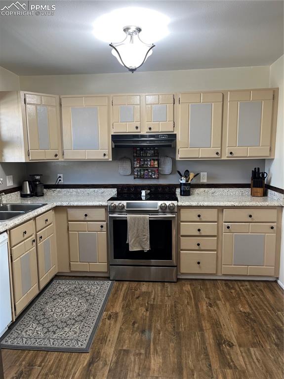 Image 9 of 29: Kitchen with stainless steel stove, a sink, light countertops, dark wood-st
