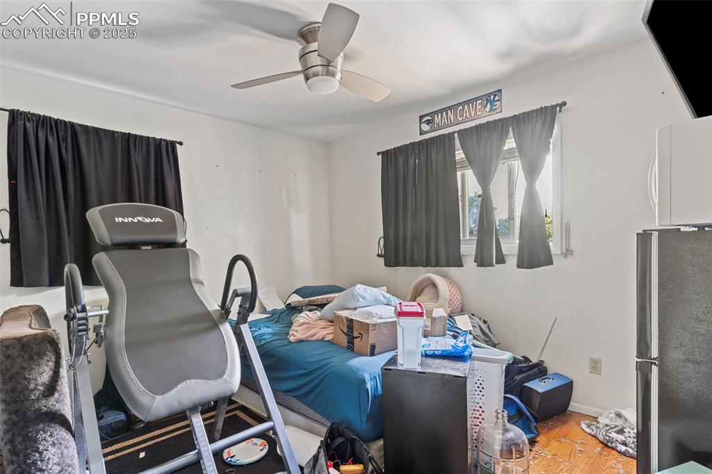 Image 12 of 25: Bedroom featuring freestanding refrigerator, wood finished floors, and a ce