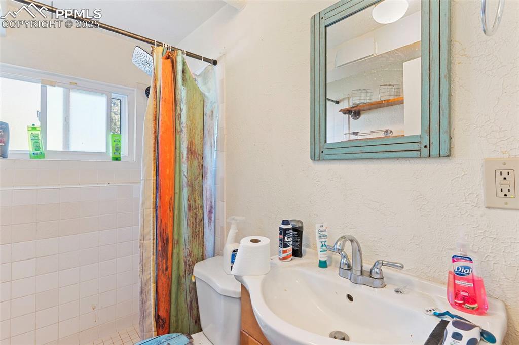 Image 15 of 25: Full bathroom featuring a textured wall, a tile shower, and vanity