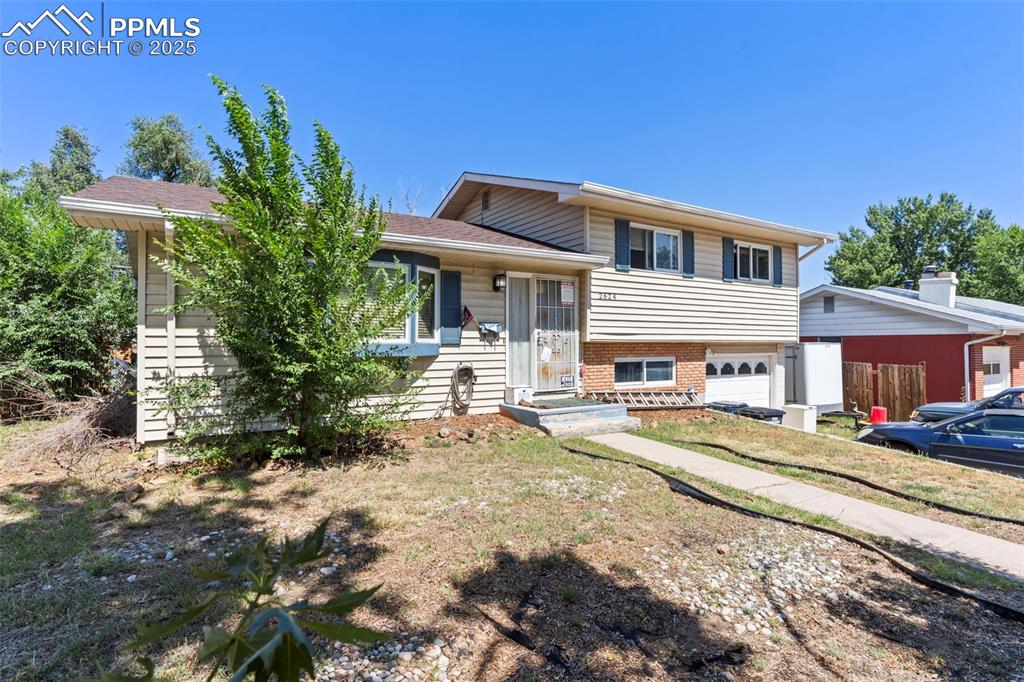 Image 2 of 25: Split level home with a garage, brick siding, and a shingled roof