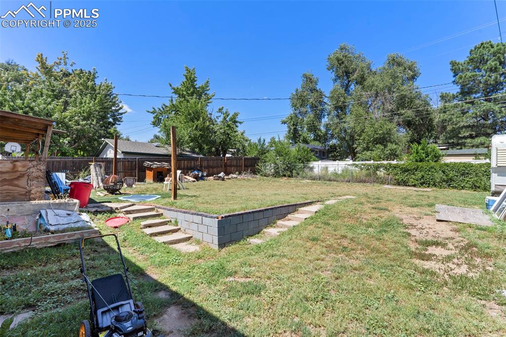 Image 22 of 25: Fenced backyard with a patio