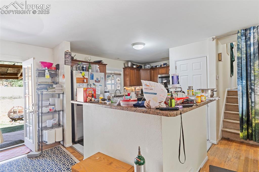 Image 6 of 25: Kitchen featuring light wood-type flooring, stainless steel appliances, dar
