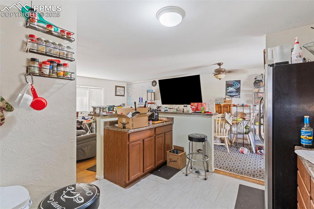 Image 7 of 25: Bar with brown cabinets, freestanding refrigerator, and a textured wall