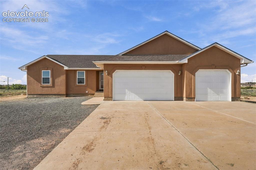 Image 1 of 50: Stucco exterior featuring a dual-bay garage, concrete driveway, and asphalt