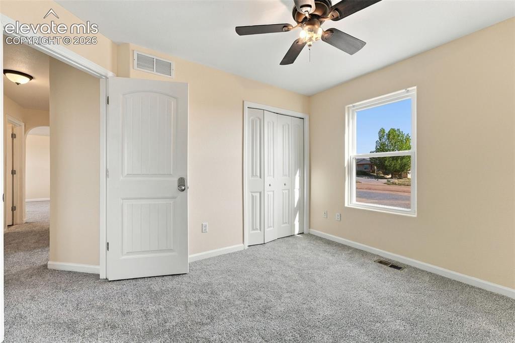 Image 10 of 50: Neutral-toned bedroom featuring carpeting, a multi-panel door, a bi-fold cl