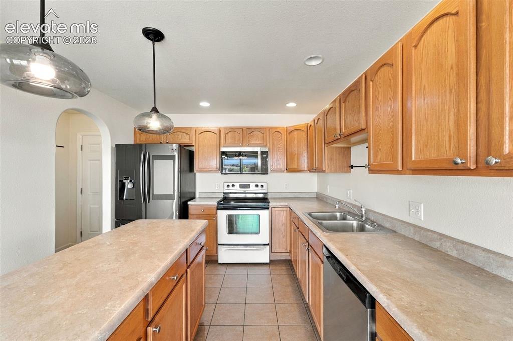Image 17 of 50: Kitchen featuring wood cabinetry, stone-finish countertops, ceramic tile fl